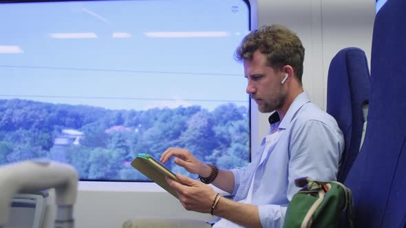Man Is Travelling By Train Viewing Pictures in Tablet