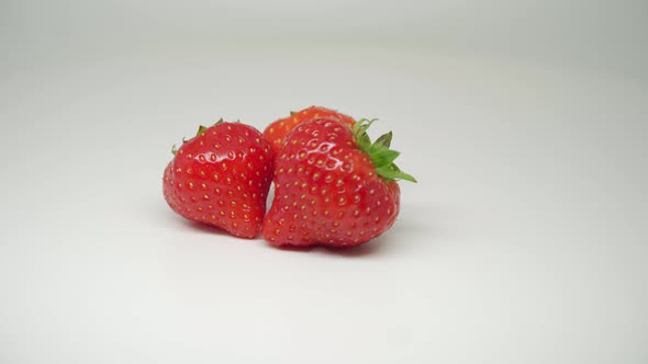 Three Delicious and Fresh Strawberries On The Rotating Table With Pure White Background - Close Up S