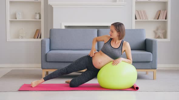 Pregnant Woman Exercise With Pilates Ball In A Living Room