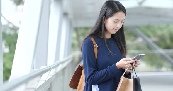 Woman look at mobile phone and holding shopping bag