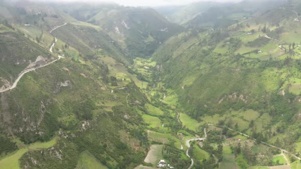 Bird eye view of a vally with a large river and a dirt road running along the edge of a cliff