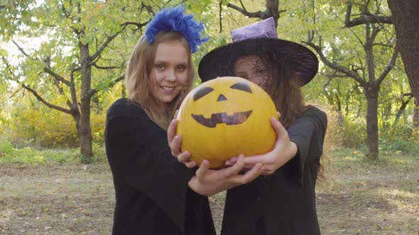 Two Cute Caucasian Children Showing Yellow Pumpkin To the Camera