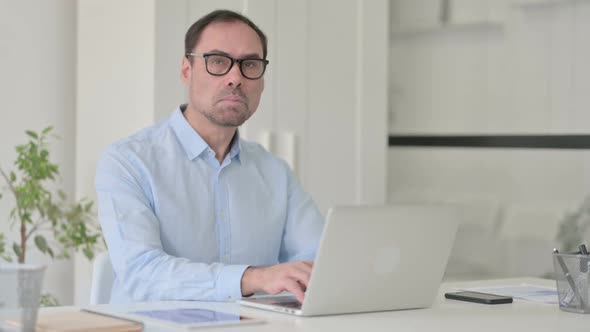 Middle Aged Man with Laptop Looking at the Camera