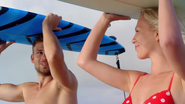 Couple carrying the surfboard on their head at beach 4k