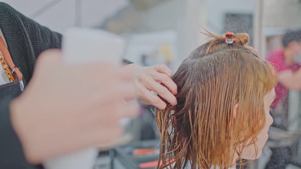 Close up of hairspray in hand of professional stylist or hairdresser spraying and making water drop