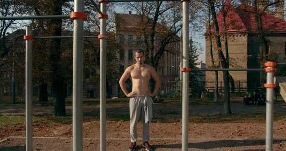 Young Man Is Standing Near Horizontal Bars After Training in Sunny Weather 