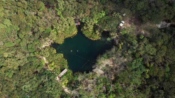 Two people swimming in pond at forest, waving at helicopter