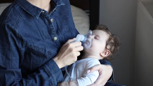 Mother making a inhalation with child on hands at home.