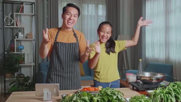 Asian Father And Daughter Streaming Live Video With Camera To Share Online While Cooking At Home