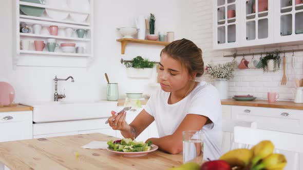 Tattooed Model Sitting at Table Feeling Sad and Unhappy with Diet Not Wanting to Eat Salad