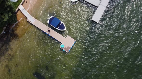 Overhead drone shot of a man walking back to shore from a dock at Lake Payette in McCall, Idaho. Thi