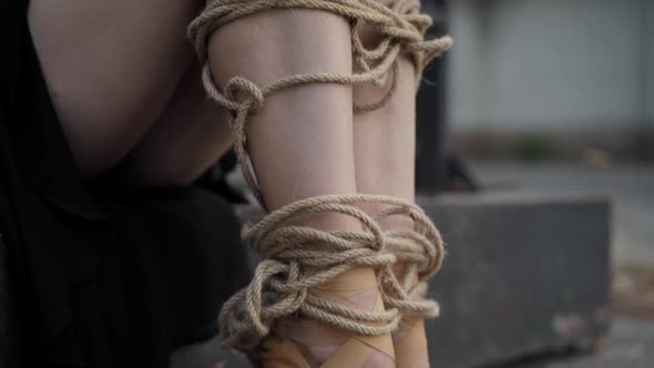 Camera Moves Down Along Slim Ballerina Legs Bound with Rope