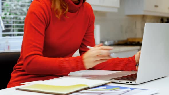 Woman using laptop in kitchen