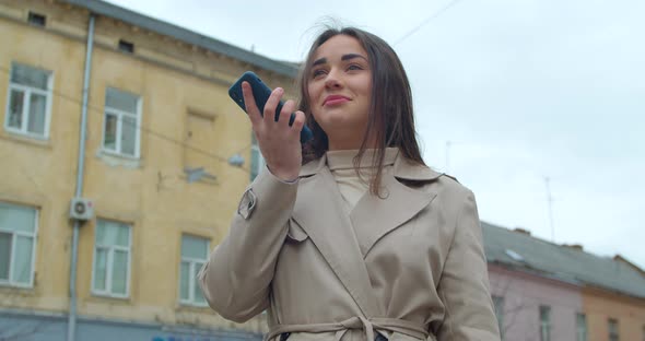 Woman Using a Smartphone Voice Recording Function Online in the City Street, Talking To Mobile