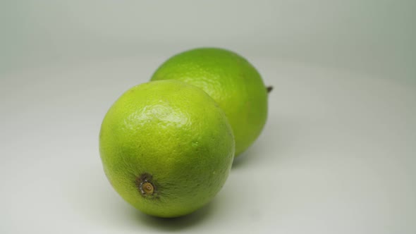 Two Green Sour Lemons Moving In Circular Motion - Close Up Shot