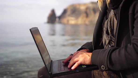 Digital Nomad a Young Tattooed Man Working Remotely Online Typing on a Laptop Keyboard While Sitting