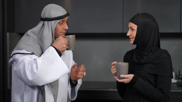 Medium Shot of Happy Middle Eastern Man and Woman Talking Drinking Coffee in the Morning at Home
