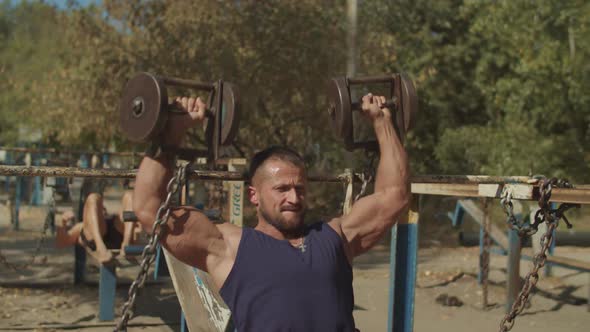 Muscular Man Doing Dumbbell Chest Press Outdoors