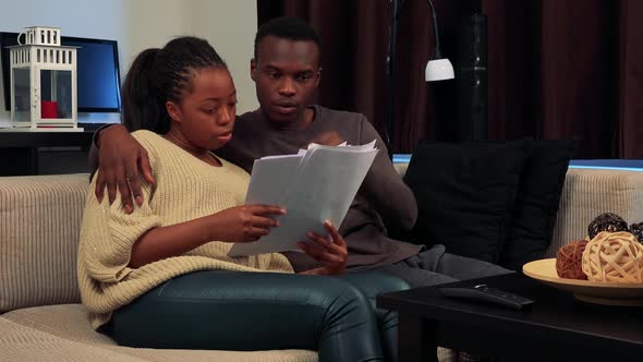 Young Black Couple Read Some Documents and Talk About It in Living Room 