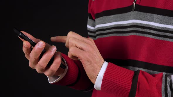 An Elderly Man Works on a Smartphone - Closeup on the Hands From the Side - Black Screen Studio