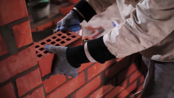 builder lays red brick close-up
