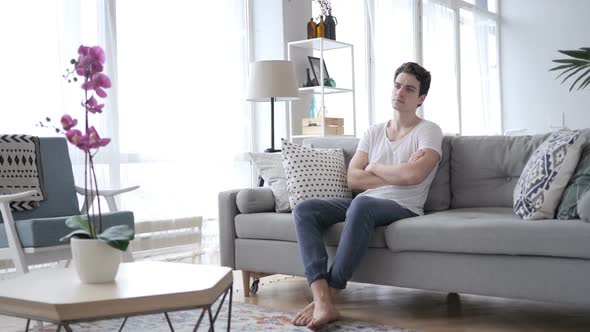 Serious Relaxing Man Sitting on Sofa at Home