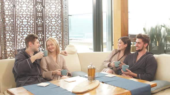 Relaxed Diverse Friends in Bathrobes Relaxing at Lounge Zone of Bathhouse