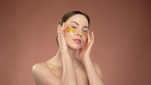 Woman with Eye Patches Touching Face