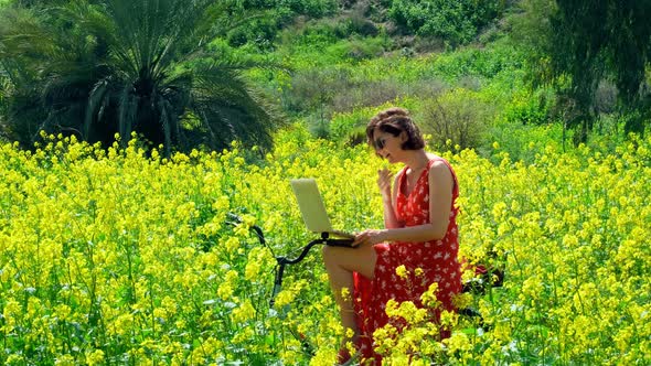 Freelancer Girl Works Behind a Laptop in a Spring Field