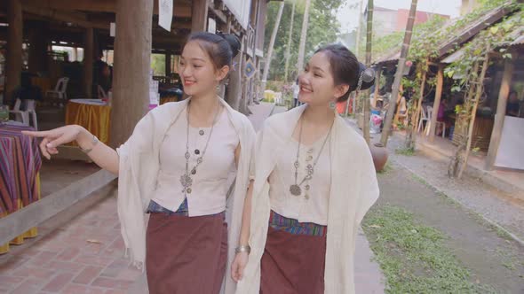 Two Teenage Girls In Thai Traditional Dress Walking Near Thai House