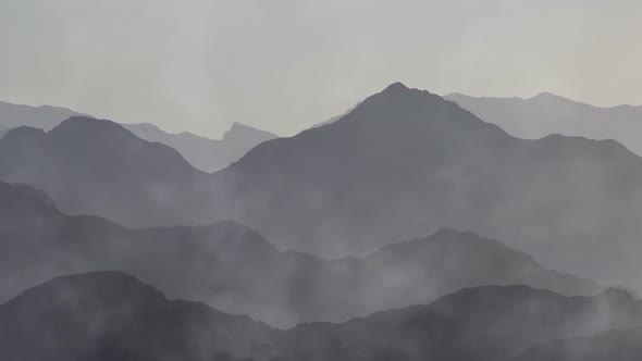 Timelapse of mist clouds over mountain silhouettes. Aerial view over mountains covered with fog.