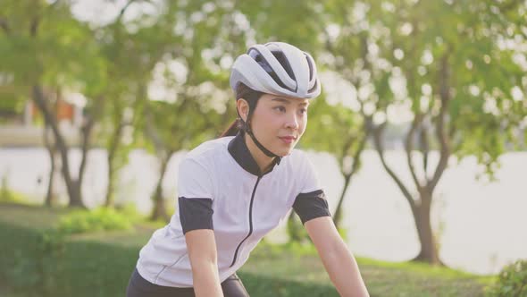 Asian young beautiful woman exercise by riding bicycle for health in the evening in public park.