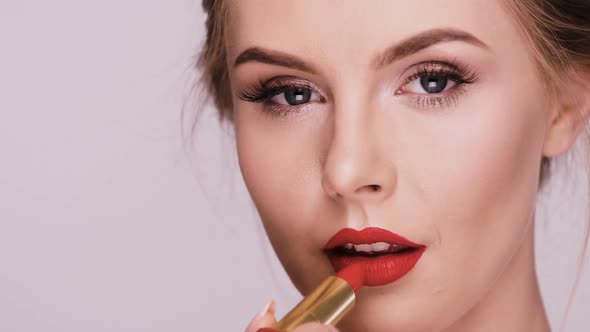 Close-up of Beautiful Woman Applying Red Lipstick and Smiling