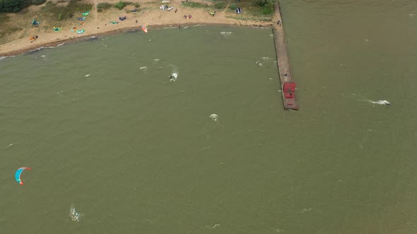 AERIAL: Reveal Shot of Bay Filled with Pro Kite Surfers Swimming in the Sea