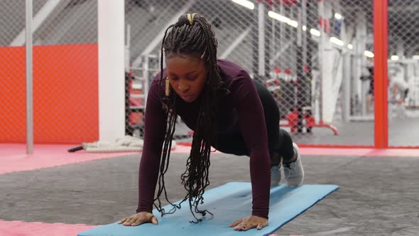 Sports Training  Africanamerican Woman Doing Push Ups on Yoga Mat in the Gym