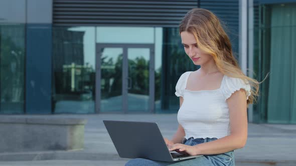 Serious Young Blonde European Lady Writing Blog or Chatting with Friends in Social Network