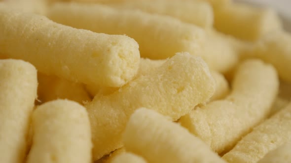 Pile of puffcorn snack in the bowl close-up slow tilt 4K 2160p 30fps UltraHD footage - Popular corn 