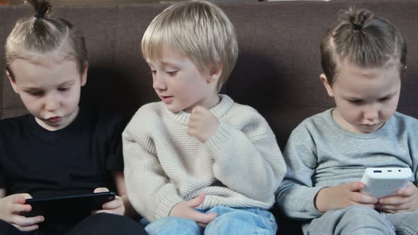 Close Up of Little Smiling Brothers Playing the Games on Mobile Phone at Home