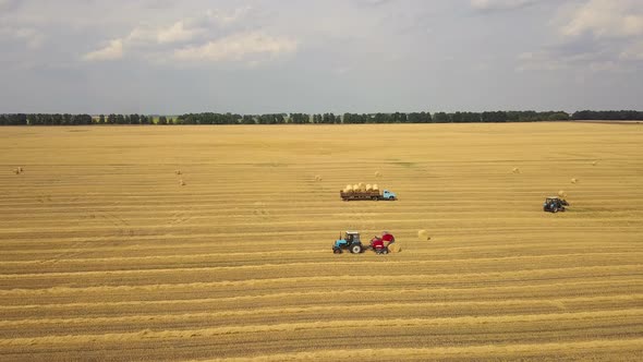 Tractor producing hay bales. Wheat field. Aerial stock footage