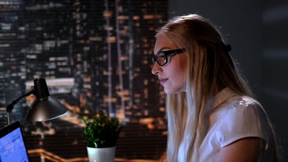 Close-up of Young Female Scientist Searching Books in Internet Late at Night