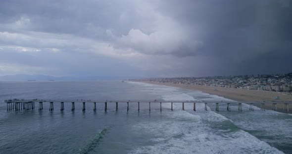 Stormy landscape of waves rolling past Manhattan Beach Pier, California, AERIAL VIEW