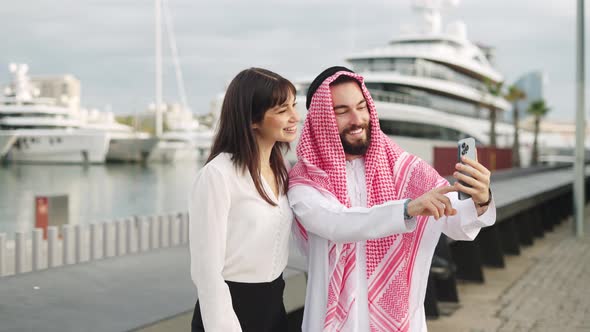 Two Smiling Multiracial Business Partners Arab Man and European Woman Taking Selfie in Port