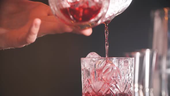 Bartender Man Pours Ruby Cocktail Into Crystal Glass