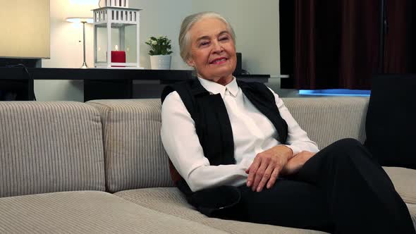 Old Happy Caucasian Woman Is Thoughtful in Living Room