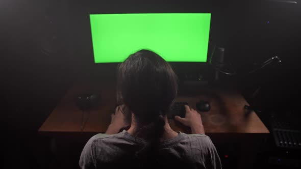 A Man Looks at the Green Screen of the Monitor