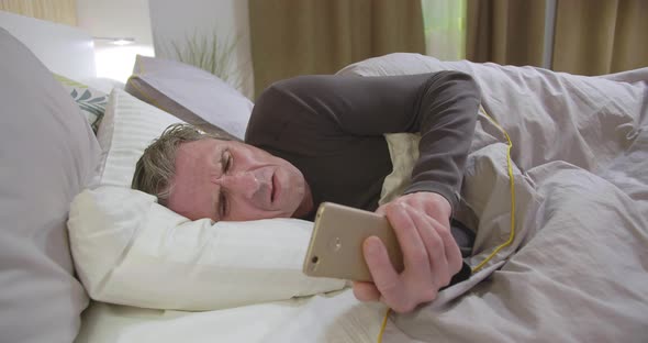 Middle-aged Man Lying on Side in Bed and Browsing Internet