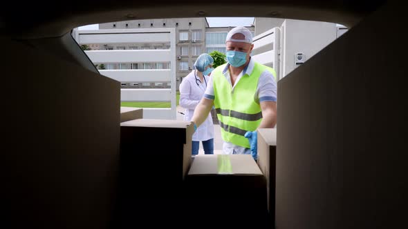 View From Car Trunk: Courier, in Protective Mask, Gloves, Unloading and Handing Boxes with Medical