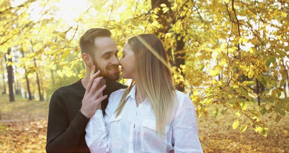 Lovely Couple in Love Stand in Sunny Autumn Park Caresses and Kisses Each Other