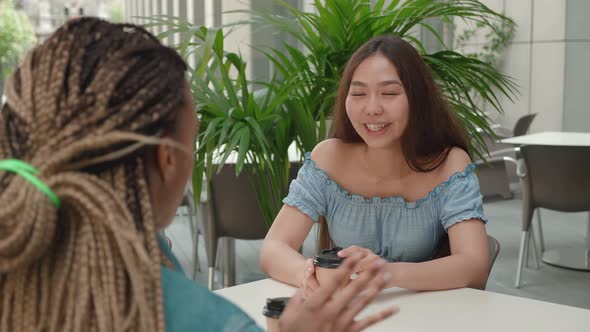 Two Female Friends Talking Outside a Coffee Shop