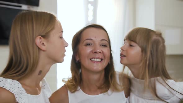 Portrait of a Beautiful Mother and Her Cute Daughters who Kisses